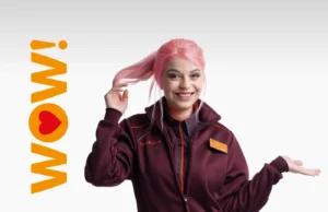 A Sainsbury's employee in their uniform standing next to the word "Wow" which we used at an event to promote their new values through the use of intelligent internal communications.
