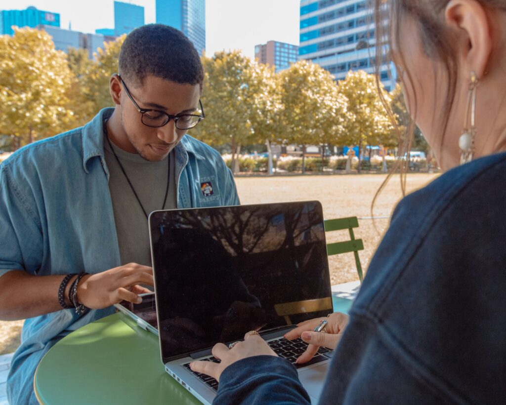 A pair of Gen Z employees working outside in a green setting with urban surroundings as part of their organisation's EVP offering.
